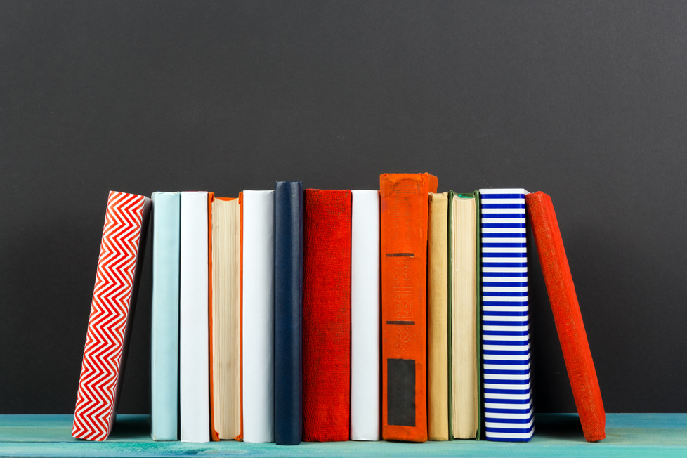 Row of colorful hardback books, open book on black background