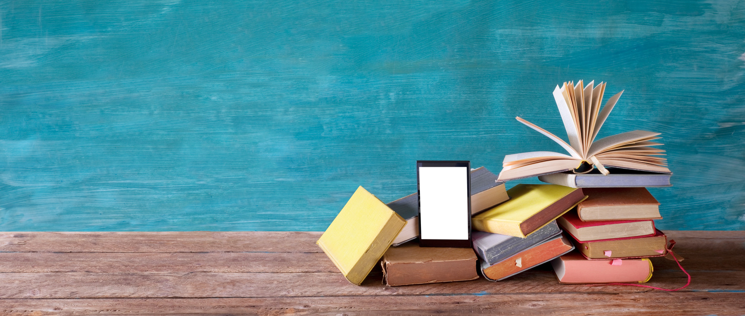 Stack of books and an e-book reader. E- Book, book fair,reading,realaxing,education concept. Free copy space on the screen of the e-book reader.